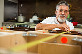Senior man doing putting together kitchen cabinets