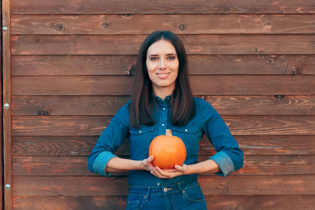 autumn girl in denim outfit holding a pumpkin - fashion women denim farm imagens e fotografias de stock