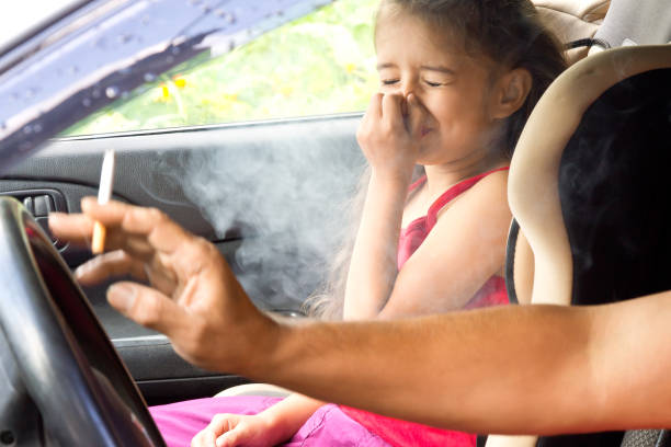 dejar de fumar para los niños. padre es fumar y la asfixia del humo en un coche - modo de vida no saludable fotografías e imágenes de stock