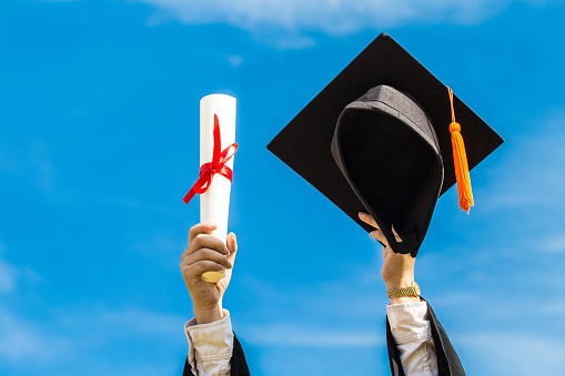 Graduate put hands up celebrating with certificate and graduation cap to the sky feeling so proud and happiness in Commencement day,Education Success Concept