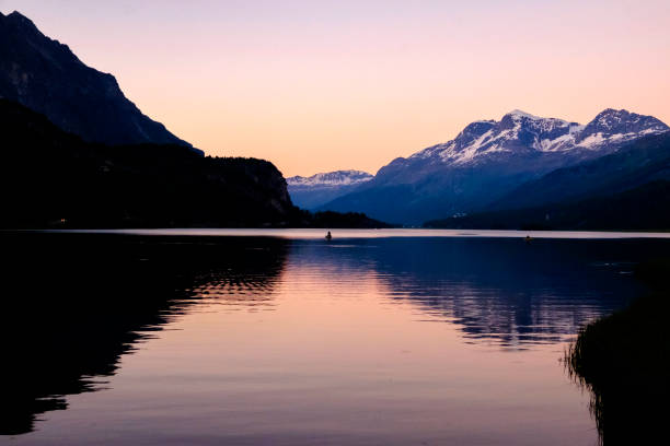 Germany, Orange sunset light on alps mountains nature landscape behind water of bodensee lake after sunset, panorama view from lindau to swiss coast and snow covered saentis peak