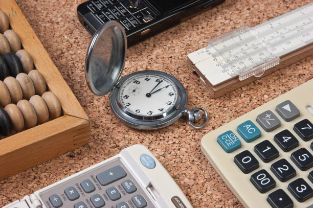 montre de poche, une calculatrice, un boulier en bois sur une planche de liège - slide rule photos et images de collection