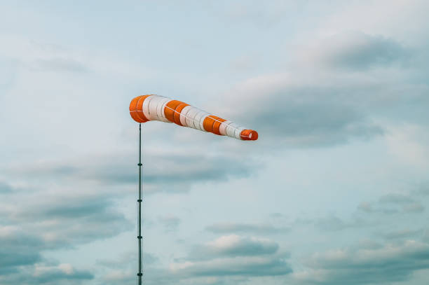 istock Striped windsock shows wind speed and direction on a background of cloudy sky 1028794352