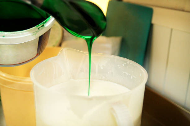 istock Confectioner in chef uniform is adding mint essence with spatula. Woman adds a mint extract and a concentrate to ice cream from a small plastic bucket using spatula. Syrup, ingredient, mint flavor. 1028803808
