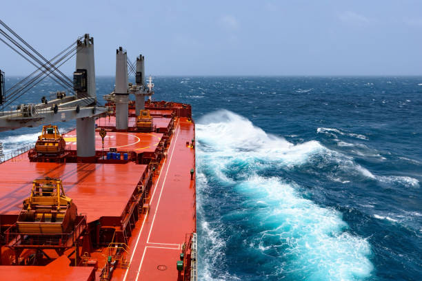 Cargo ship rolling in stormy Indian Ocean Cargo ship rolling in stormy sea. Huge waves under blue sky in Indian Ocean bulk carrier stock pictures, royalty-free photos & images