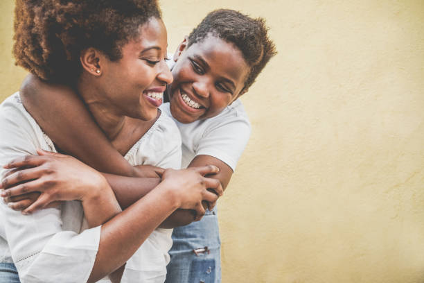 felice giovane madre che si diverte con suo figlio - figlio che abbraccia sua madre all'aperto - stile di vita familiare, maternità, amore e concetto di momenti teneri - concentrati sul viso del bambino - child caribbean black latin american and hispanic ethnicity foto e immagini stock