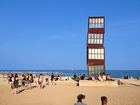 Barcelona, Spain - June 2, 2014: Young people at Barceloneta beach surrounding the work of art by Rebecca Horn \