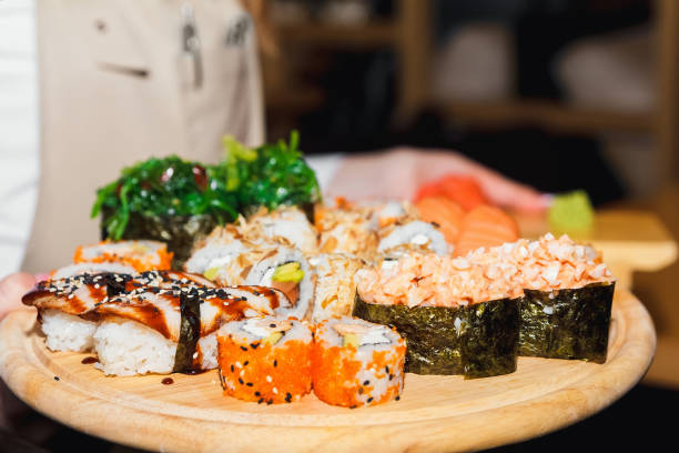 istock Sushi california salmon on a white rectangular plate in the waiter's hand close-up 1028853728