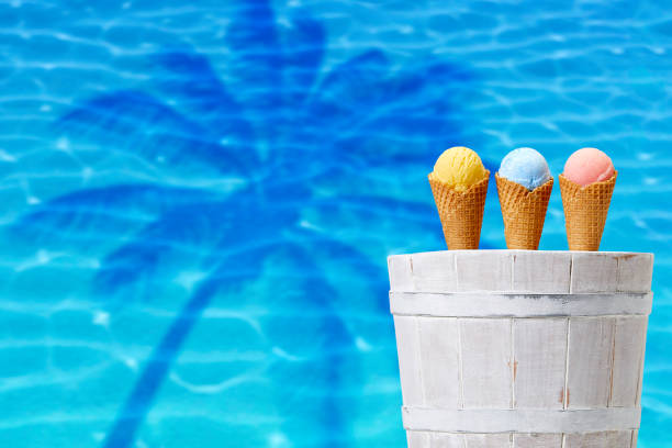 istock Ice cream cones in white bucket on blue water and palm background 1028857096