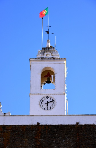 Alandroal, Évora district, Portugal: clock tower with weather vane and Portuguese flag, 19th century construction on top of a 13th century tower - Torre do relógio sobre a Torre de Menagem