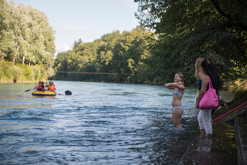 Bern, Switzerland - August 15, 2018: A young woman prepares to dive into the Aare River in Bern, Switzerland. Floating down the river is a popular summer activity in Bern.