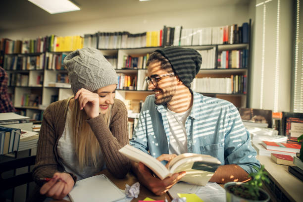 istock Cute hipster modern in love couple sitting in a library and looking through some studying books. 1028870028