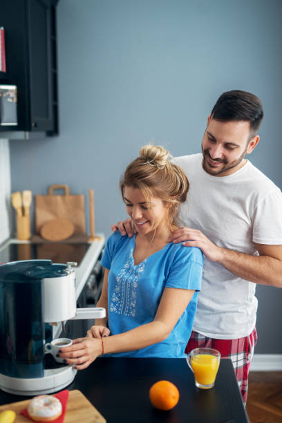 istock Handsome sweet man giving his girlfriend a massage while she is preparing coffee in their kitchen early in a morning. 1028872910