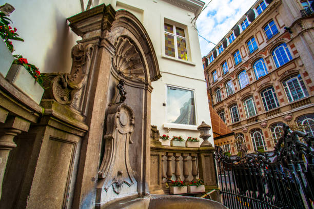 Brussels (Bruxelles), Belgium - March 21, 2018 - Street view of Mannekin Pis on a corner of the center of Brussels Mannekin Pis or le Petit Julien is the famous statue of little boy urinating into a fountain's basin designed by Hieronymus Duquesnoy the Elder manneken pis statue in brussels belgium stock pictures, royalty-free photos & images
