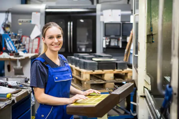 young blond woman is programming a CNC milling machine