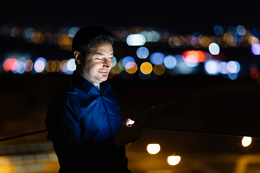 A businessman is using a digital tablet at night.