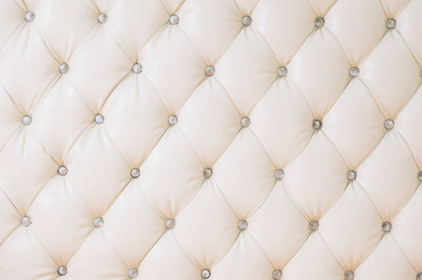 istock Beige soft tapestry pattern background with symmetrical buttons on the corners of diamonds. Soft and expensive furniture elements. Luxury background 1028892994