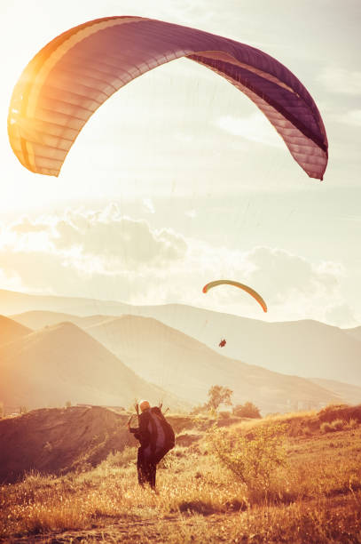 parapente sport extrême avec des montagnes sur le concept de mode de vie sain et de la liberté fond vacances d’été - skydiving air aerial view vertical photos et images de collection