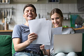 Happy couple laughing having fun with documents and laptop