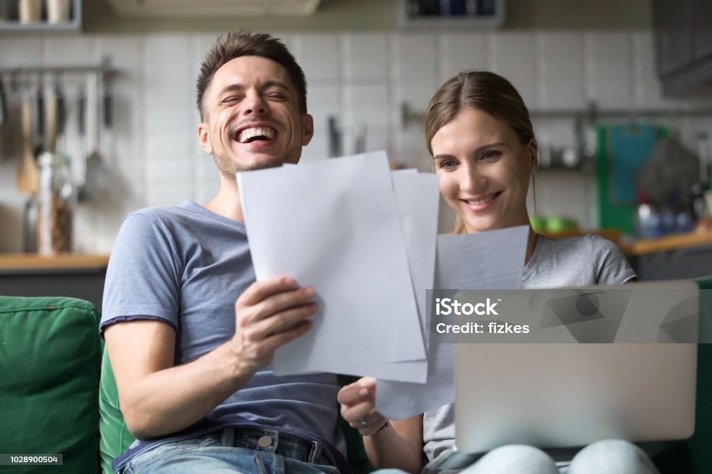 Happy couple laughing having fun with documents and laptop - Royalty-free Conta - Acessório Financeiro Foto de stock
