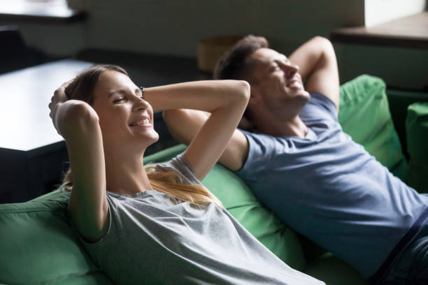 istock Smiling couple resting on comfortable couch taking break for relaxation 1028900538