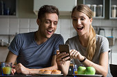 Excited couple surprised by unbelievable good news looking at smartphone