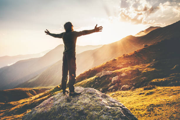Happy Man raised hands at sunset mountains Travel Lifestyle emotional concept stock photo