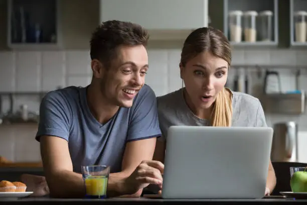 Photo of Surprised couple amazed with online shopping sale looking at laptop