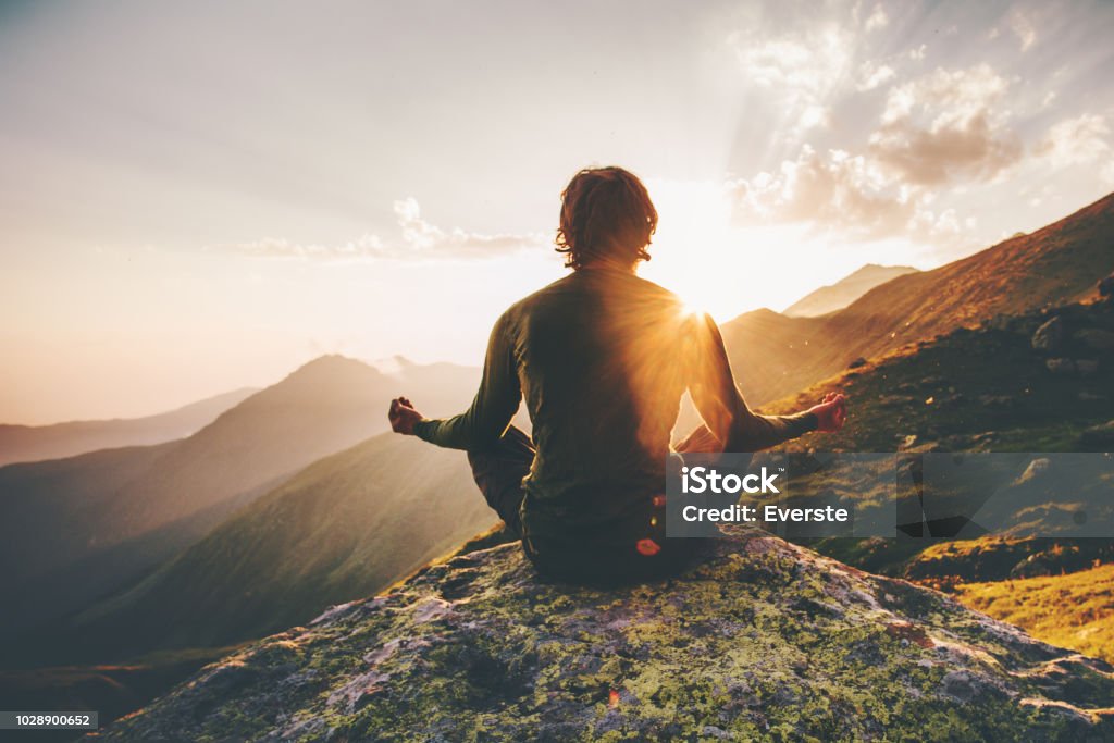 Uomo meditando yoga sulle montagne del tramonto Travel Lifestyle relax concetto emotivo avventura vacanze estive armonia all'aperto con la natura - Foto stock royalty-free di Meditare