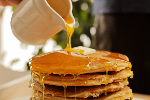istock Chef pouring maple syrup over stacked pancakes 1028901100