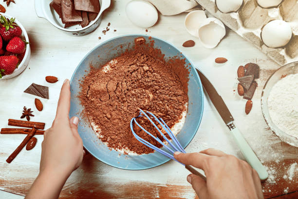 istock Cropped image of attractive young woman cooking a chocolate pie. Ingridients on white rustik background. Eggs, chocolate, milk, spices. 1028907022