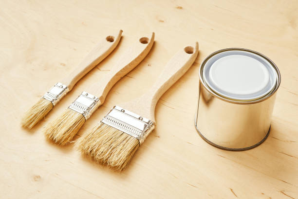 istock three brushes and a silver paint can on a wooden board 1028910090