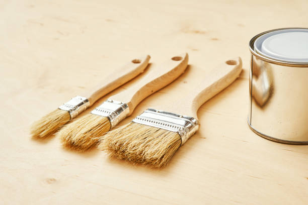 istock three brushes and a silver paint can on a wooden board 1028910160