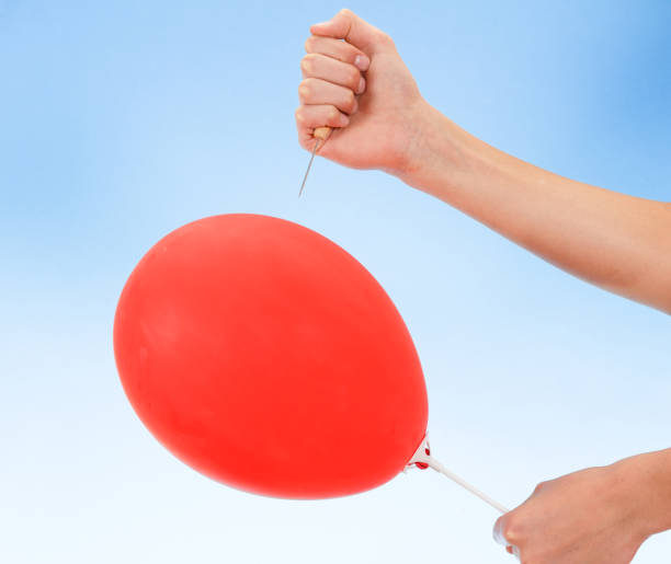 istock hand holding needle near balloon. isolated on white. Danger concept. 1028914166