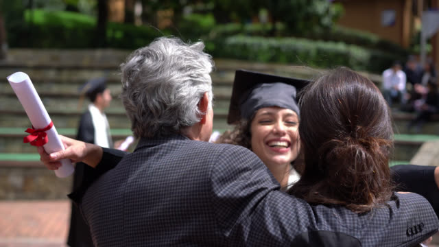 Excited daughter running to celebrate and hug her parents after receiving her degree at colllege