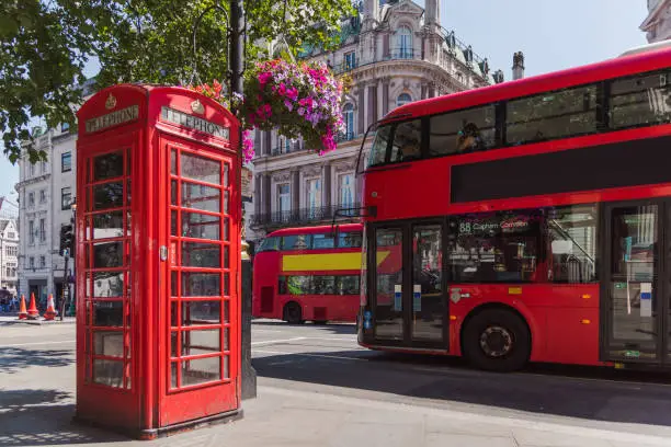 red phone booth with colored flowers and red bus, england, great britain, london