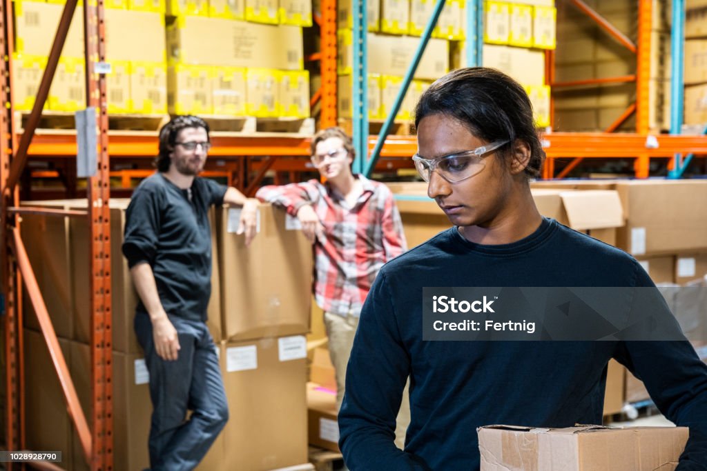 An industrial warehouse worker being the target of bullying An industrial warehouse worker being the target of bullying, abuse or discrimination. Bullying Stock Photo