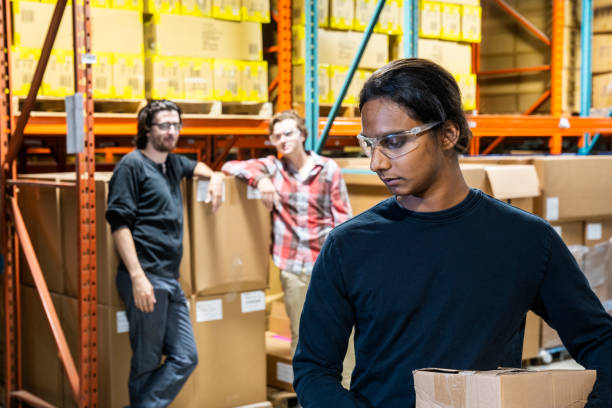 An industrial warehouse worker being the target of bullying An industrial warehouse worker being the target of bullying, abuse or discrimination. harassment stock pictures, royalty-free photos & images