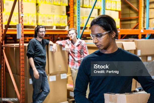 An Industrial Warehouse Worker Being The Target Of Bullying Stock Photo - Download Image Now