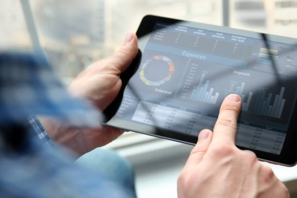 Business man working and analyzing financial figures on a graphs on a tablet  in  the office