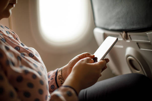 istock Businesswoman using mobile phone in the airplane 1028944774