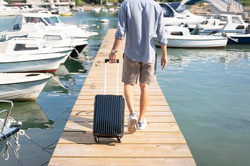 Male tourist leaving the docks with a carry-on luggage