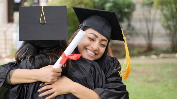 istock Young graduate hugs friend tightly after ceremony 1028962532