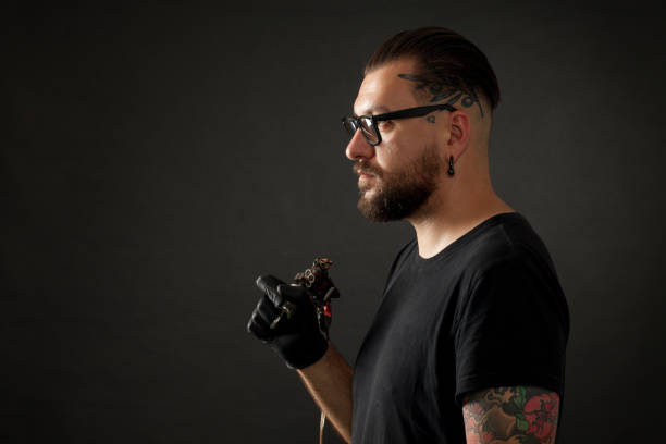 retrato de estudio de un artista del tatuaje en un fondo negro - tattoo men profile punk fotografías e imágenes de stock