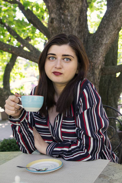 プラスサイズの女性の夏の公園で、若い女性の若い女性は公園で都市通りのカフェのテーブルでコーヒーを飲む - gaining weight audio ストックフォトと画像