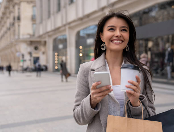 istock Shopping woman texting on her phone and drinking coffee 1028983466