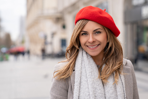 Portrait of a beautiful woman in Paris wearing a beret and looking at the camera smiling - lifestyle concepts