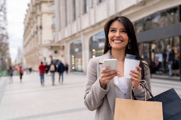 istock Shopping woman texting on her phone and drinking coffee 1028983542