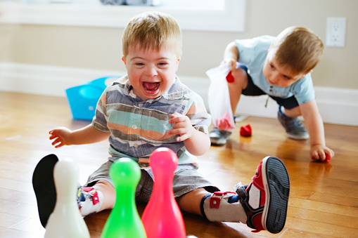 Three years old Child with Down syndrome wearing an orthopedic device playing. These games, bowling, are exercises to help him strengthen his legs Color and horizontal Photo was taken in Quebec Canada.