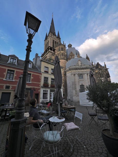 istock Young man sitting in cafe in front of Aachen cathedral 1029047088